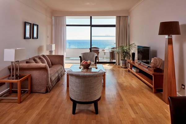 Wohnzimmer mit Meerblick im Grecian Bay Hotel mit Möbeln und Fernseher.