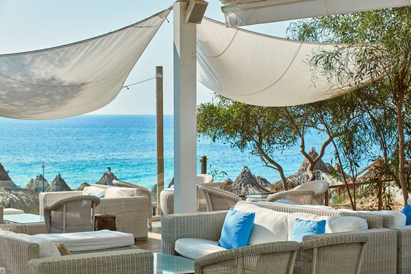 Außenbereich des Grecian Bay Hotels mit Blick auf das Meer und umgeben von Bäumen.