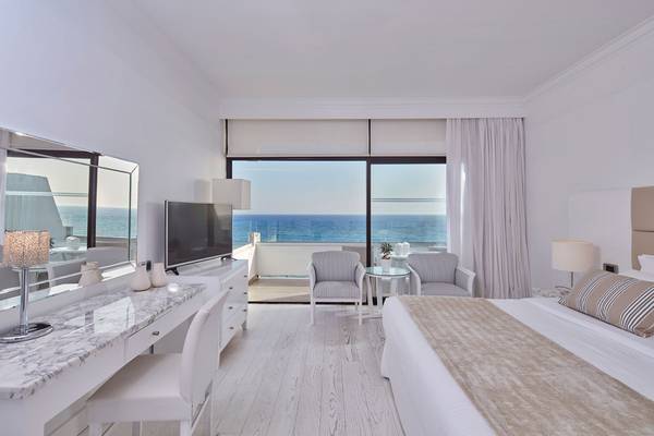 Schlafzimmer im Grecian Bay Hotel mit Meerblick, großem Bett und moderner Einrichtung.