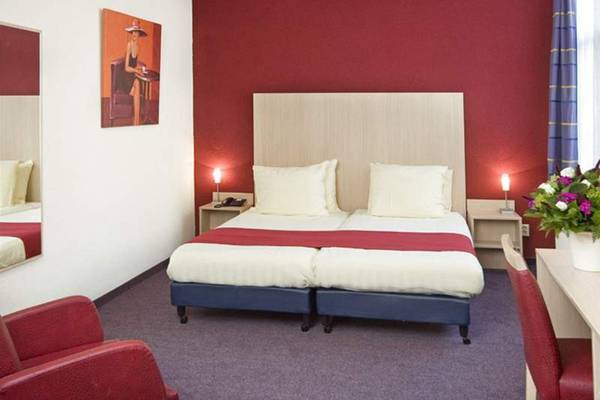 Doppelzimmer im Nova Hotel mit zwei Betten, roten Wänden und einem Kunstwerk an der Wand.
