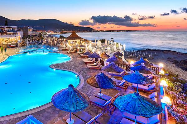 Alexander Beach Hotel & Village Resort am Abend mit Swimmingpool und Sonnenliegen.
