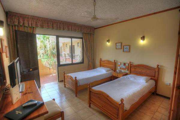 Zwei Betten in einem Hotelzimmer der Cornucopia Bungalows mit Balkonzugang.