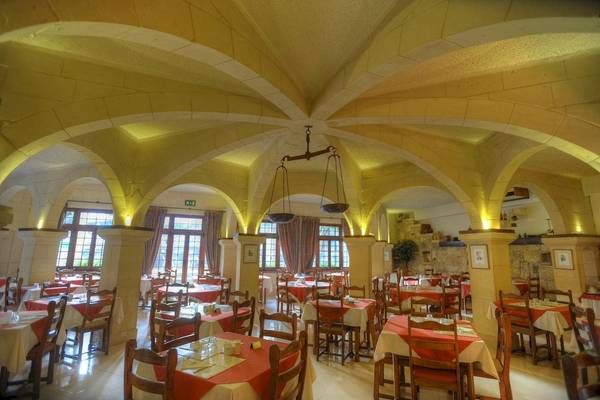 Innenansicht des Restaurants Cornucopia Bungalows mit vielen Tischen und Stühlen, gelben Wänden und Decken mit Bögen.