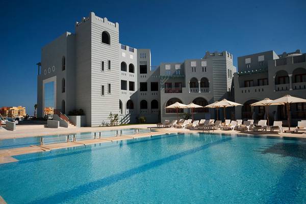 Außenbereich des Fanadir Hotel El Gouna mit Swimmingpool und Liegestühlen unter Sonnenschirmen.
