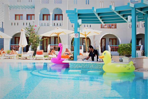 Poolbereich mit Gästen und Hotelpersonal, Flamingo- und Enten-Schwimmtier.