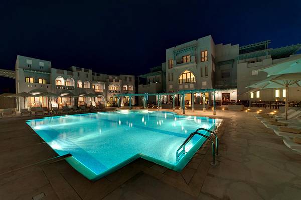 Der Außenpool des Fanadir Hotel El Gouna bei Nacht mit Loungestühlen und Sonnenschirmen