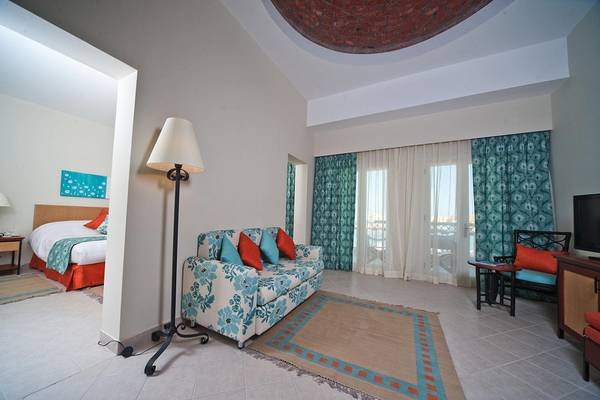 Hotelzimmer im Fanadir Hotel El Gouna mit Bett, Sofa, Tisch, Lampe und Fernseher.