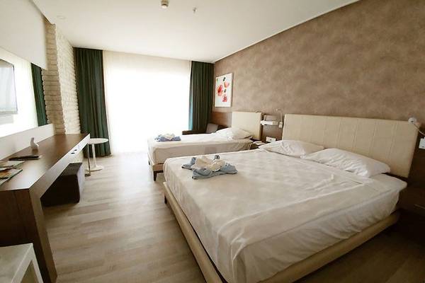 Schlafzimmer im Gold Island Hotel mit zwei Betten, einem Schreibtisch und einer Lampe.