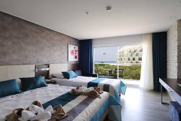 Doppelzimmer im Gold Island Hotel mit Meerblick, zwei Betten, Dekor und Ausblick auf eine Gebäudeanlage.