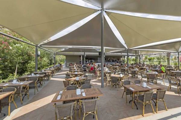 Outdoor-Restaurant im Royal Seginus Hotel mit vielen Gästen unter Sonnensegeln.