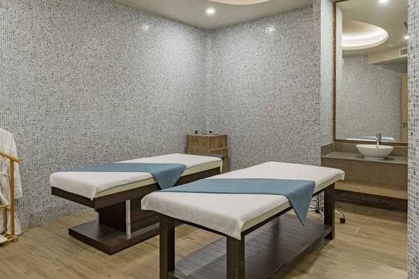 Behandlungsraum im Royal Seginus Hotel mit zwei Massagetischen und einem Bademantelhaken.