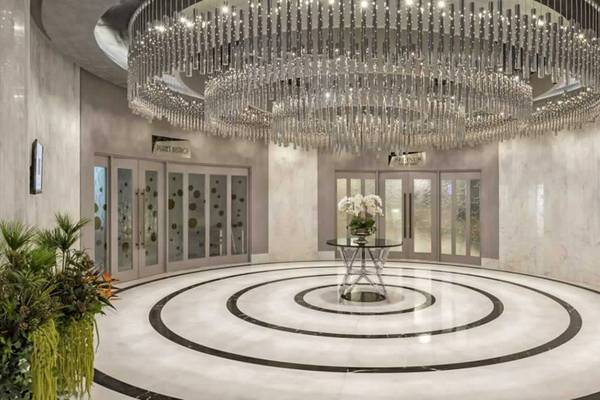 Empfangsbereich des Royal Seginus Hotels mit großem Kristallkronleuchter und moderner Inneneinrichtung.