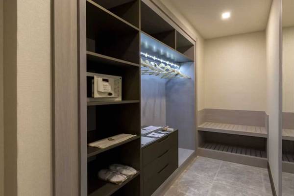 Ein moderner begehbarer Kleiderschrank im Royal Seginus Hotel mit eingebautem Safe und Beleuchtung.
