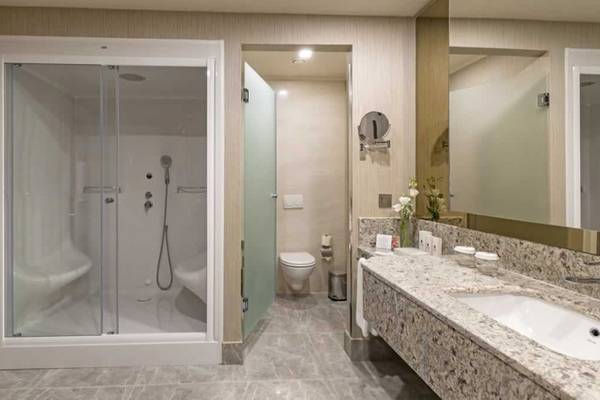 Badezimmer im Royal Seginus Hotel mit Glasdusche, Toilette und Waschbecken.