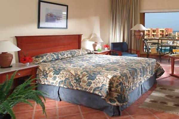 Hotelzimmer im Magic Tulip Resort mit Bett, Nachttischen, Lampe, Pflanzen und Balkon.