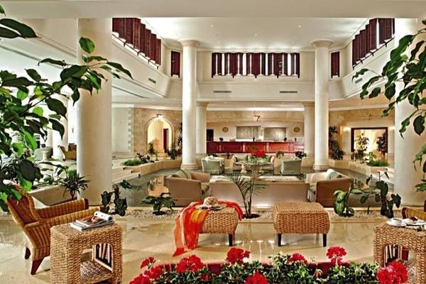 Innenansicht der Lobby des Magic Tulip Resort mit großen Säulen, Pflanzen, Sofas und Tischen.
