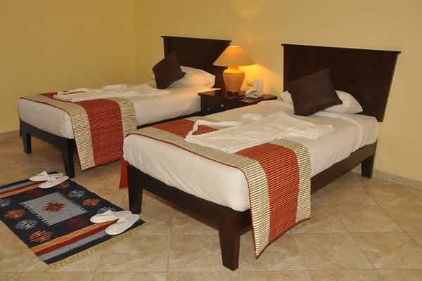 Zwei Betten im Zimmer des Magic Tulip Resort mit Kissen, Decken und Nachttischen.
