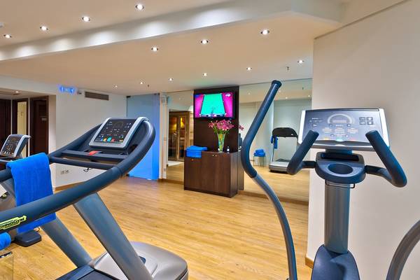 Fitnessraum im Kriti Beach Hotel mit Laufband, Fernseher und Trainingsgeräten.