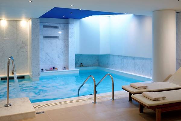 Innenpool im Kriti Beach Hotel mit weißen Marmorwänden und zwei Liegestühlen