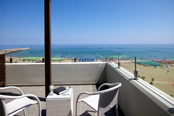 Terrasse mit Meerblick im Kriti Beach Hotel mit zwei weißen Stühlen und einem kleinen Tisch davor.
