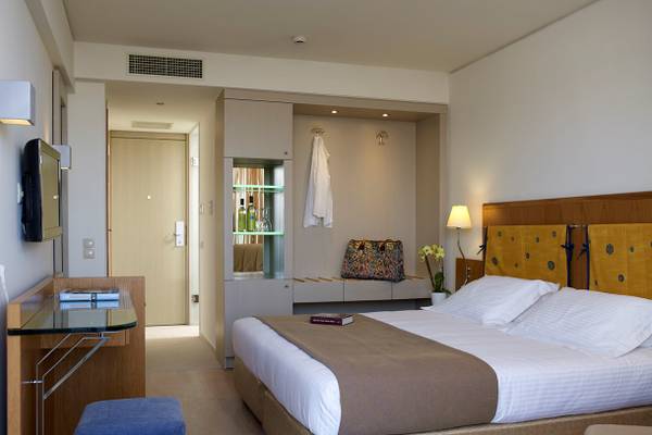 Ein elegantes Hotelzimmer im Kriti Beach Hotel mit einem großen Bett und einem Schreibtisch.