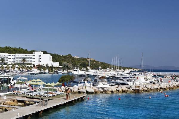 Altin Yunus Hotel & Spa Marina mit vielen Booten am Kai und Liegestühlen.