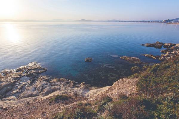 Aussicht auf das Meer und Felsen bei Sonnenaufgang mit sanften Wellen und Horizont