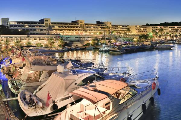 Ein Hotel namens Altin Yunus Hotel & Spa, das viele Boote im Hafen hat, bei Nacht.