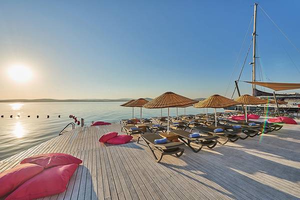 Terrasse des Altin Yunus Hotel & Spa mit Sonnenliegen und Sonnenschirmen am Wasser