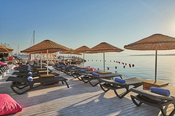 Reihe von Sonnenliegen mit Sonnenschirmen am Strand des Altin Yunus Hotel & Spa.
