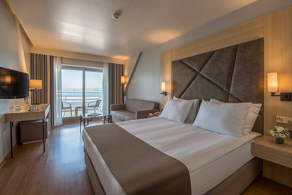 Innenansicht eines Zimmers im Altin Yunus Hotel & Spa mit Bett, Sofa, Fernseher und Aussicht.