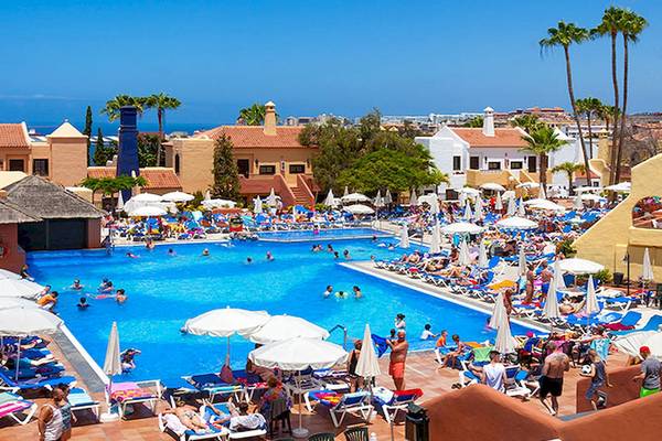 Luftaufnahme des Poolbereichs des Tagoro Family & Fun Costa Adeje Hotels mit vielen Gästen und Sonnenschirmen