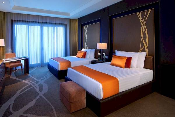 Zwei Betten in einer Hotelsuite des Anantara Eastern Mangroves Abu Dhabi Hotels mit Schreibtisch und Fernseher