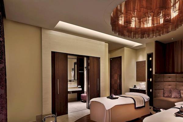 Spa-Bereich im Anantara Eastern Mangroves Abu Dhabi Hotel mit zwei Behandlungsbetten, einem Kronleuchter und Möbeln.