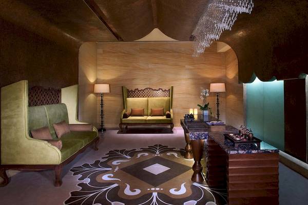 Loungebereich im Anantara Eastern Mangroves Abu Dhabi Hotel mit grünen Sofas, Wandleuchten und einem zentralen Tisch.