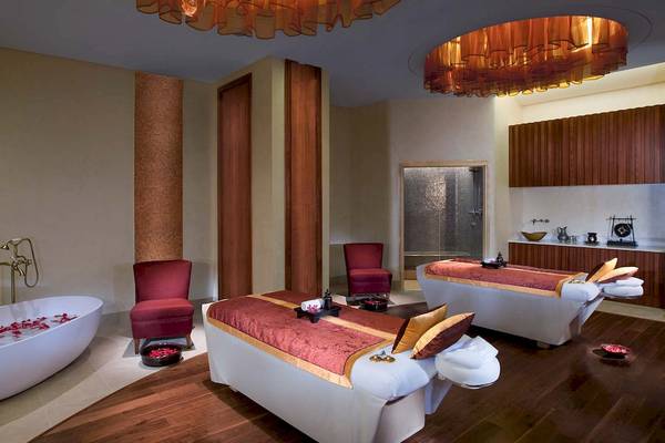 Spa-Behandlungsraum im Anantara Eastern Mangroves Abu Dhabi Hotel mit Badewanne, Liegen und Möbeln.