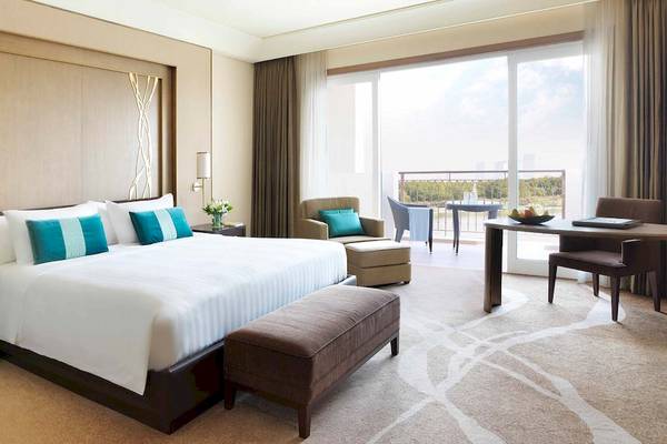 Innenansicht eines Hotelzimmers im Anantara Eastern Mangroves Abu Dhabi Hotel mit großem Bett, Balkon und Aussicht