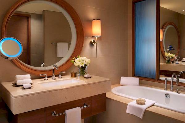 Luxuriöses Badezimmer im Anantara Eastern Mangroves Abu Dhabi Hotel mit Badewanne, Waschbecken und Spiegeln.