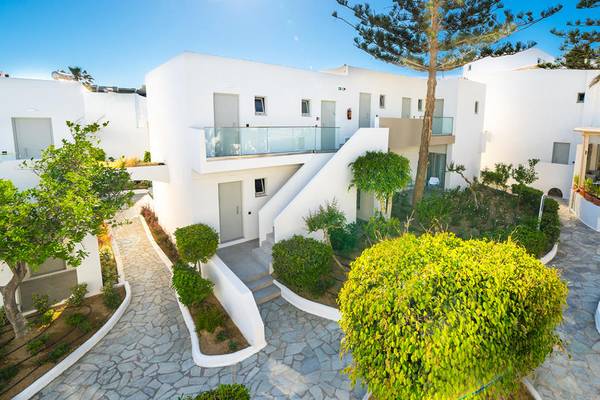 Außenansicht des Adele Beach Hotels mit weißen Gebäuden, Treppen und gepflegten Gärten.