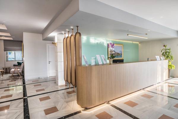 Reception im Adele Beach Hotel mit modernem Holztresen und stilvollen Dekorationen.