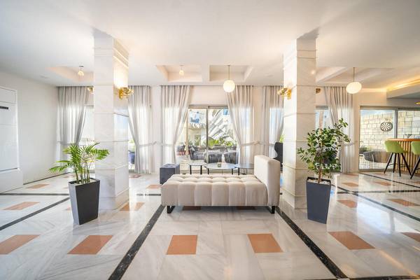 Empfangsbereich des Adele Beach Hotels mit weißem Marmorboden, hohen Säulen und modernen Möbeln.
