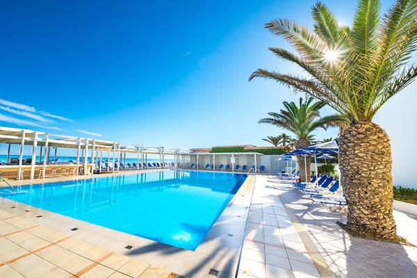 Außenpool des Adele Beach Hotels mit Sonnenliegen und Palmen an einem sonnigen Tag.