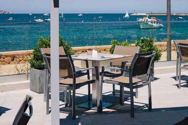 Terrasse des NYX Ibiza Hotels mit Blick auf das Meer und mehrere Boote im Hintergrund.