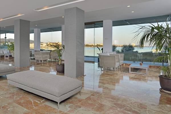 Hotellobby des NYX Ibiza Hotels mit Blick auf das Meer und Palmen im Hintergrund.