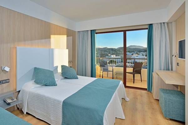 Innenansicht eines Hotelzimmers im NYX Ibiza Hotel mit zwei Betten, Balkon und Blick auf die Stadt.