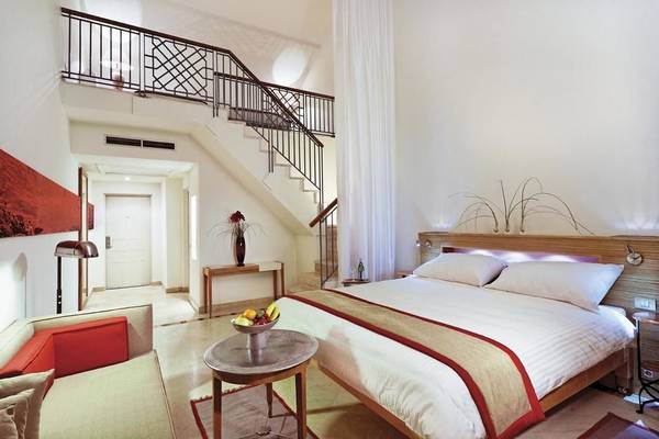 Schlafzimmer im Mövenpick Resort & Spa El Gouna mit Bett, Tisch und Früchteschalen.