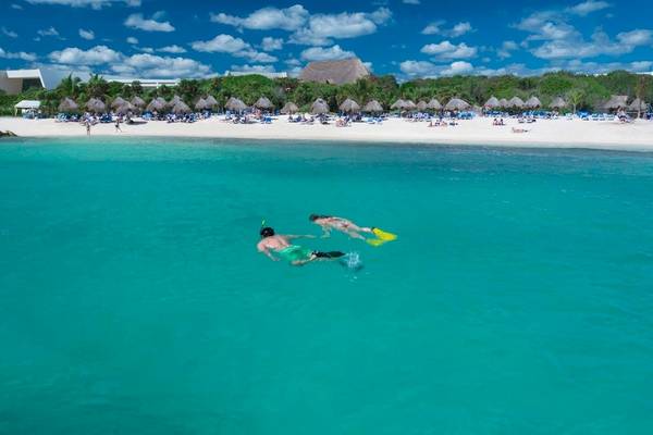 Zwei Personen schnorcheln im kristallklaren Wasser vor dem Grand Sirenis Riviera Maya Resort & Spa.