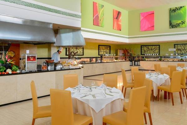 Innenansicht des Restaurants im Grand Sirenis Riviera Maya Resort & Spa mit Buffet, Kellner und gedeckten Tischen.