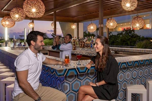 Ein Paar sitzt an einer Bar im Grand Sirenis Riviera Maya Resort & Spa und genießt Cocktails.