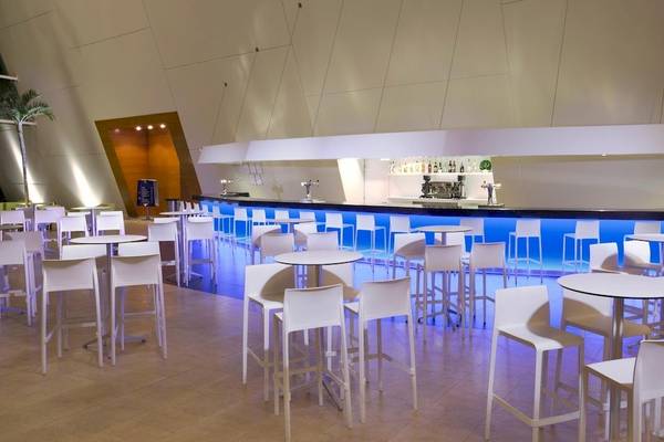 Barbereich im Grand Sirenis Riviera Maya Resort & Spa mit weißen Stühlen und blauen Leuchtlichtern.
